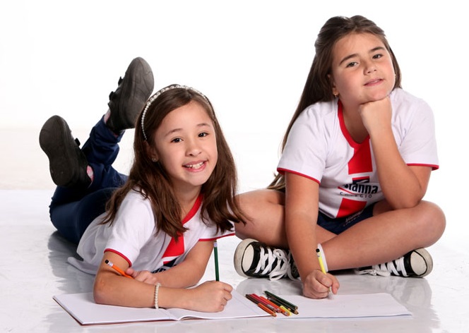 Uma estudante do Vianna deitada no chão escrevendo em seu caderno e outra estudante do Vianna sentada no chão escrevendo em seu caderno. Ambas olhando para a foto.